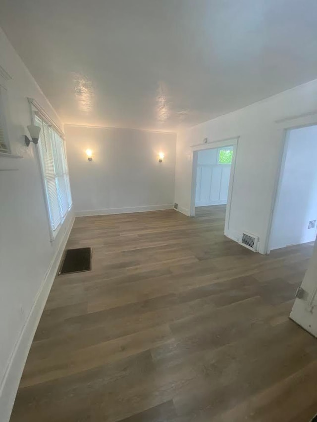 empty room featuring dark wood-style floors, baseboards, and visible vents