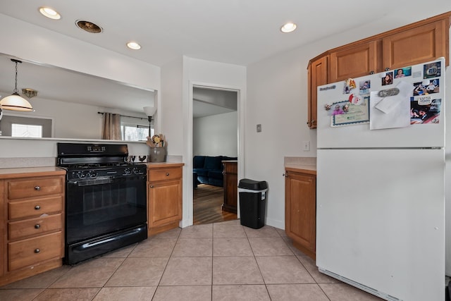 kitchen featuring black range with gas cooktop, hanging light fixtures, light tile patterned floors, and white refrigerator