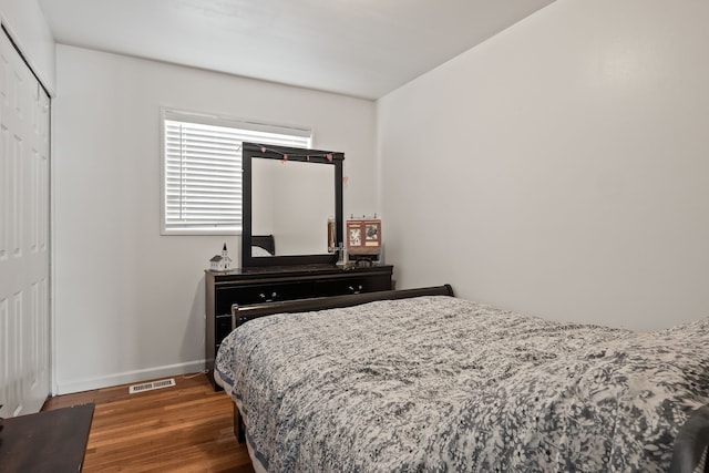 bedroom with dark hardwood / wood-style floors and a closet