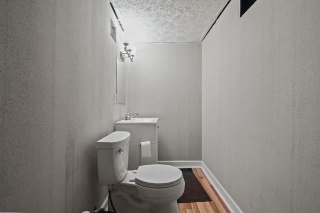 bathroom featuring vanity, hardwood / wood-style floors, a textured ceiling, and toilet