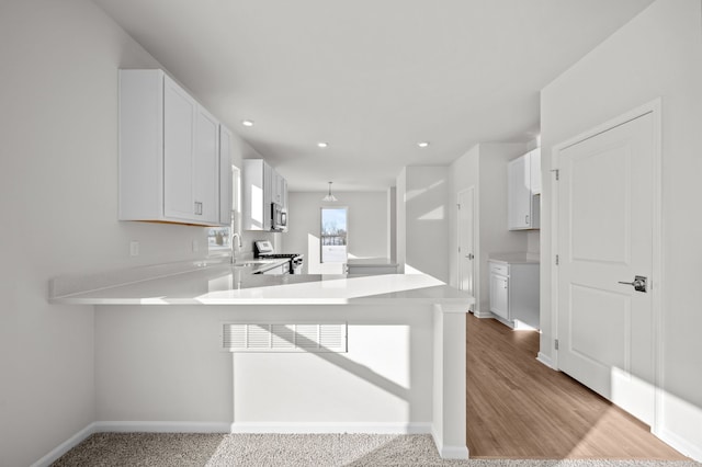 kitchen featuring stainless steel appliances, light countertops, a sink, a peninsula, and baseboards