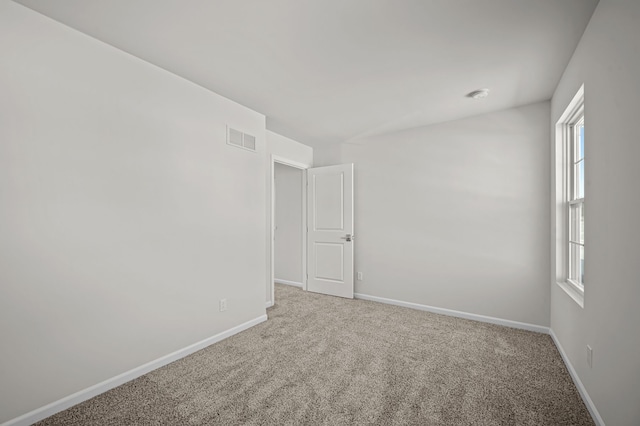 spare room featuring carpet, visible vents, and baseboards