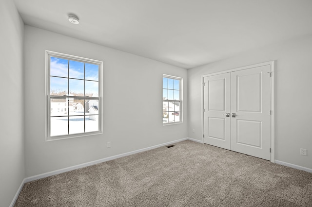 unfurnished bedroom with a closet, carpet flooring, visible vents, and baseboards