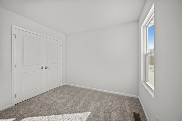 unfurnished bedroom with carpet, a closet, visible vents, and baseboards