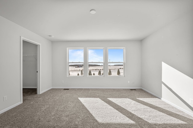 unfurnished room featuring carpet, visible vents, and baseboards