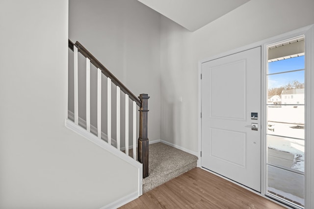 foyer entrance featuring stairs, wood finished floors, and baseboards