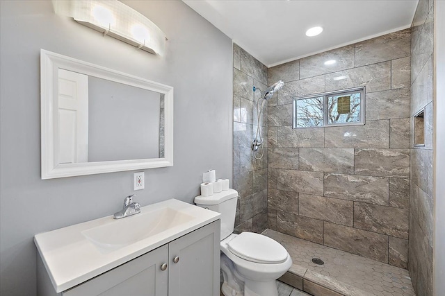 bathroom with vanity, tiled shower, and toilet