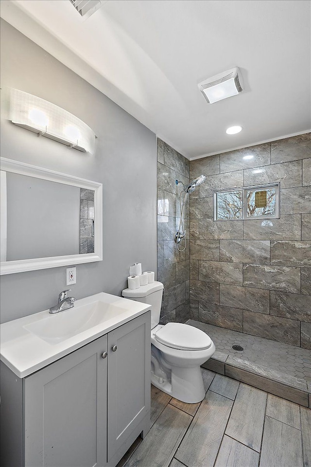 bathroom featuring vanity, toilet, and tiled shower