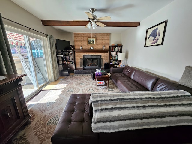 living room with a brick fireplace, beamed ceiling, and ceiling fan