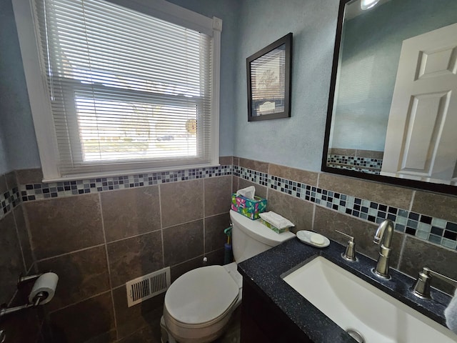 bathroom featuring vanity, tile walls, and toilet