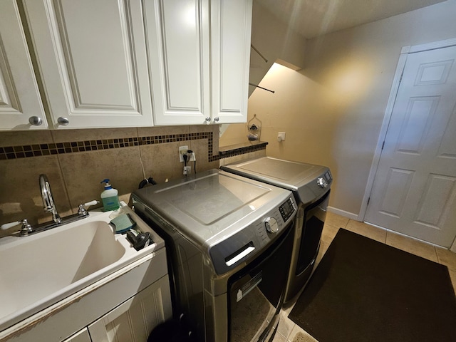 clothes washing area with cabinets, sink, light tile patterned floors, and washing machine and clothes dryer