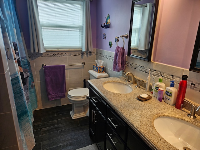 bathroom featuring vanity, a healthy amount of sunlight, tile walls, and toilet