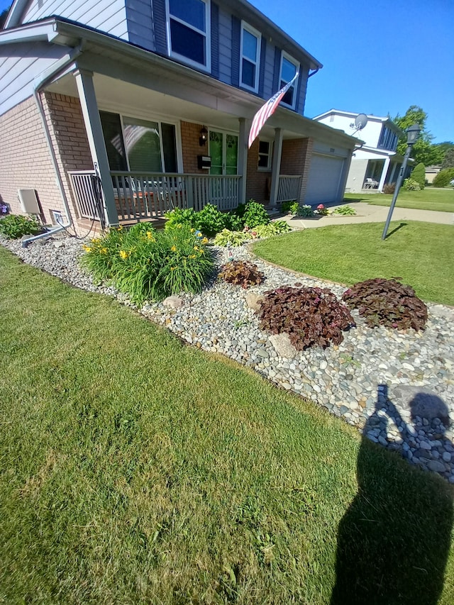 view of front facade featuring a garage, a front yard, and covered porch