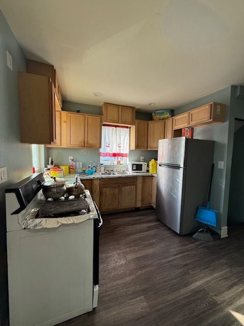 kitchen featuring dark hardwood / wood-style flooring, stainless steel refrigerator, sink, and gas range oven