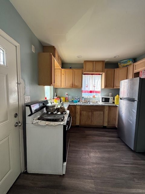 kitchen with electric stove, sink, dark hardwood / wood-style flooring, and stainless steel refrigerator