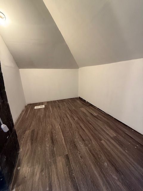 bonus room with dark wood-type flooring and lofted ceiling