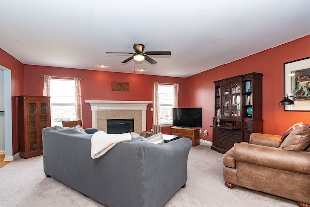 carpeted living room featuring ceiling fan, a tiled fireplace, and a wealth of natural light