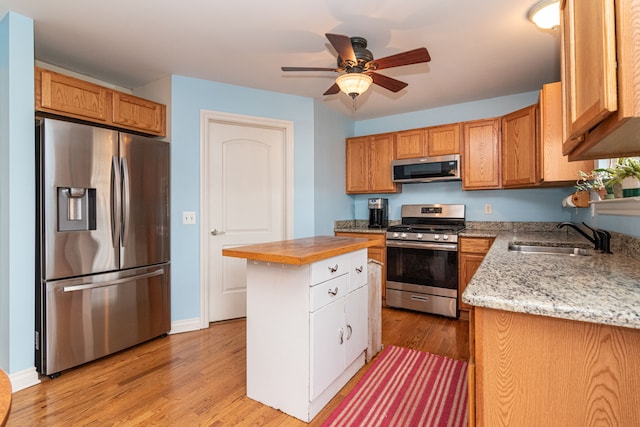 kitchen with a center island, appliances with stainless steel finishes, sink, and light hardwood / wood-style flooring