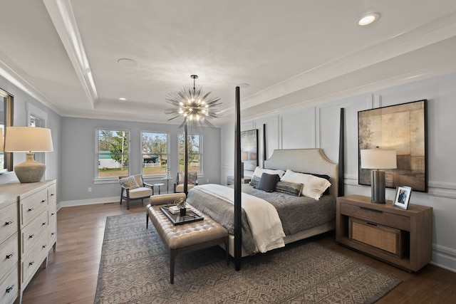 bedroom featuring dark wood-type flooring, ornamental molding, a tray ceiling, and an inviting chandelier