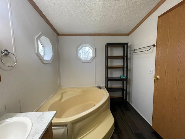 bathroom with ornamental molding, a tub, vanity, and a textured ceiling