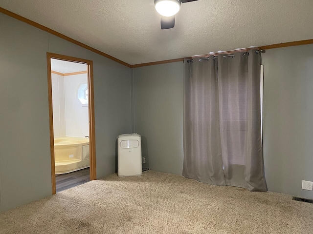 carpeted empty room with crown molding, vaulted ceiling, and a textured ceiling