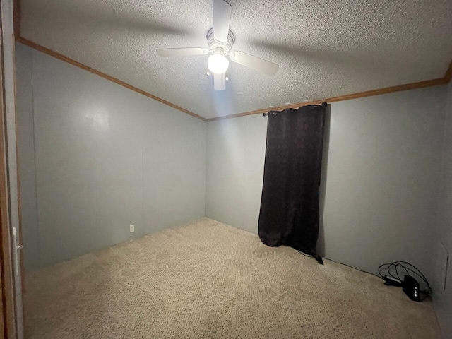 empty room with crown molding, ceiling fan, carpet floors, and a textured ceiling