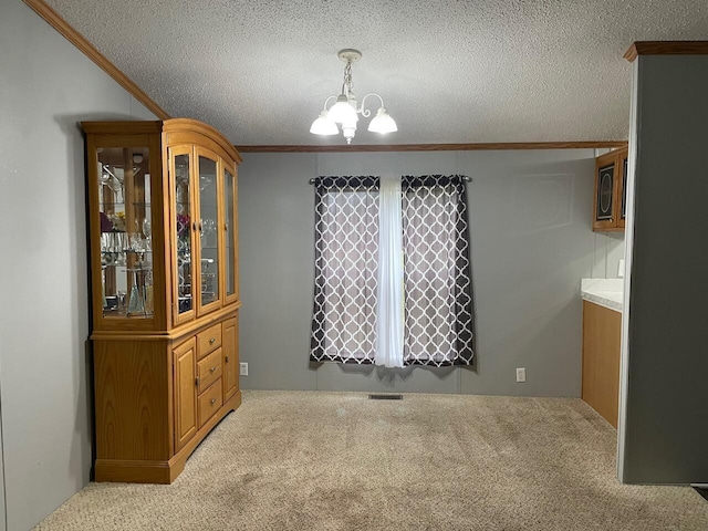 unfurnished dining area featuring an inviting chandelier, ornamental molding, light colored carpet, and a textured ceiling