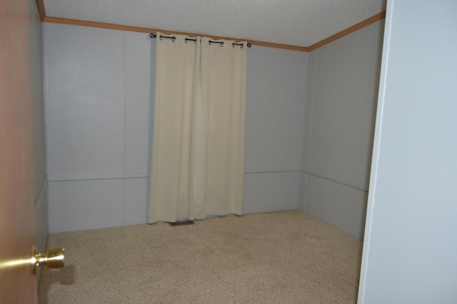 carpeted spare room featuring crown molding and a textured ceiling