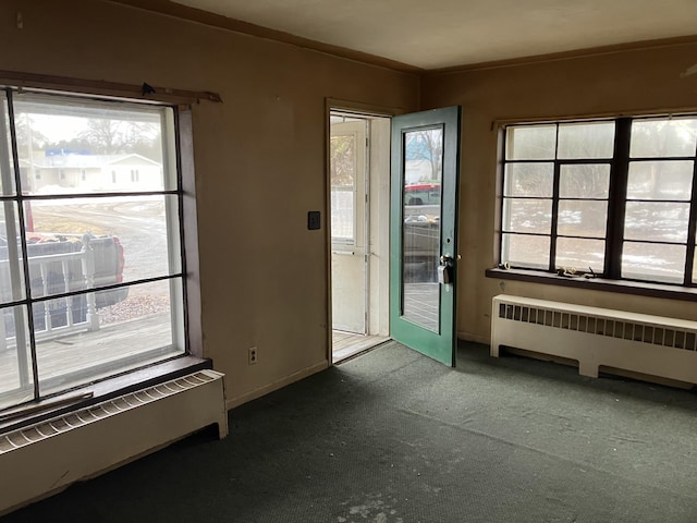 doorway to outside with baseboards, carpet floors, and radiator