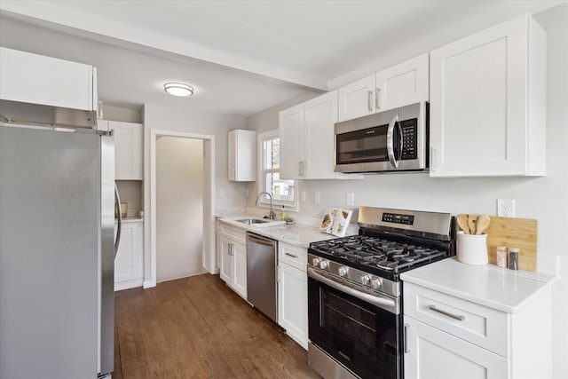 kitchen with sink, white cabinetry, stainless steel appliances, light stone countertops, and dark hardwood / wood-style flooring