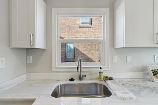 kitchen featuring sink, light stone countertops, and white cabinets