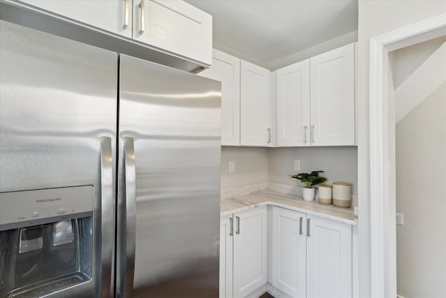 kitchen featuring white cabinetry, light stone counters, and stainless steel fridge with ice dispenser