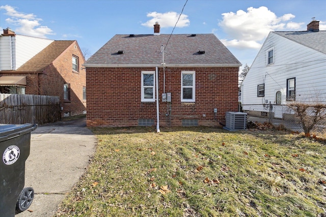 rear view of property with central AC and a lawn