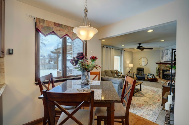 dining room with ceiling fan and a fireplace