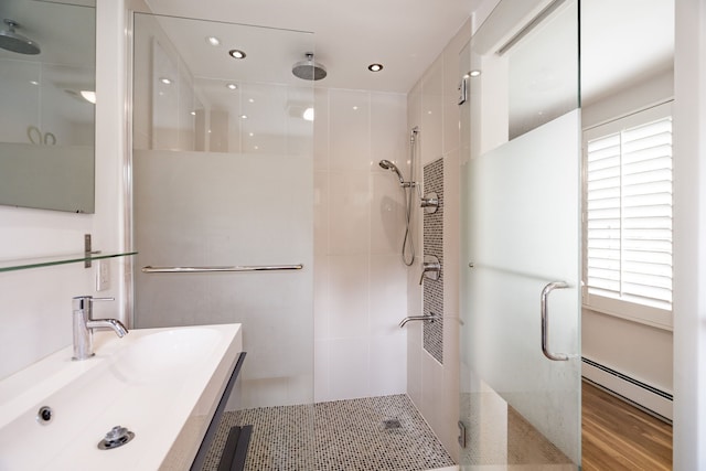 bathroom with a wealth of natural light, a baseboard radiator, hardwood / wood-style flooring, and walk in shower