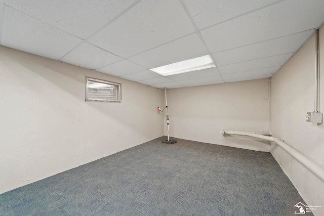 basement with a paneled ceiling and carpet