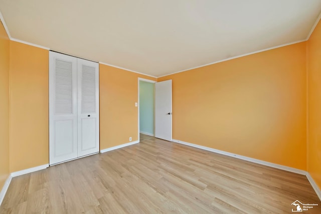 unfurnished bedroom featuring crown molding, a closet, and light hardwood / wood-style flooring