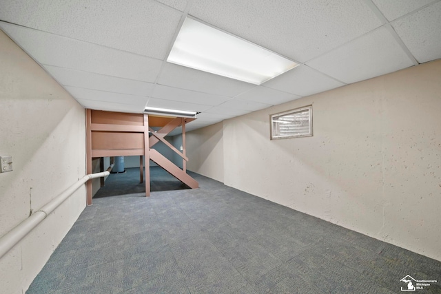 basement with dark colored carpet and a drop ceiling