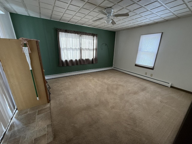 carpeted empty room featuring a drop ceiling, a baseboard radiator, and ceiling fan