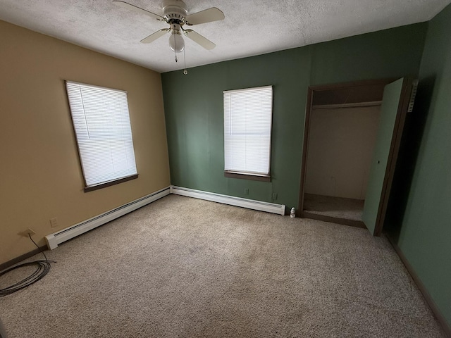 unfurnished bedroom with ceiling fan, carpet, a baseboard heating unit, and a textured ceiling