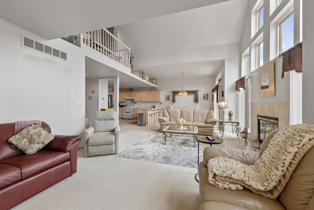 carpeted living room featuring a tiled fireplace and a high ceiling