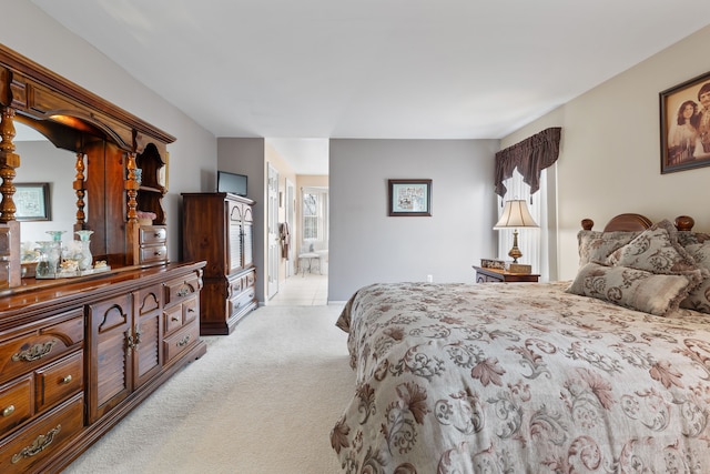 bedroom with ensuite bathroom and light carpet