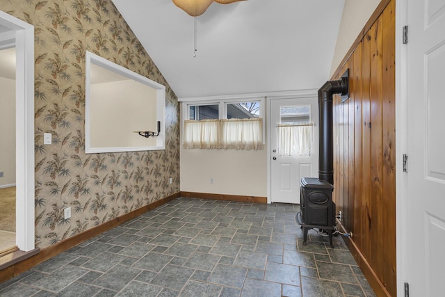 interior space with vaulted ceiling, ceiling fan, and a wood stove