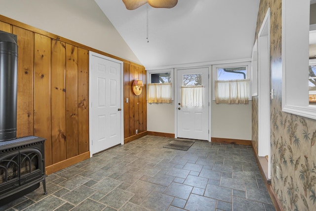 foyer entrance with vaulted ceiling, a wood stove, and ceiling fan