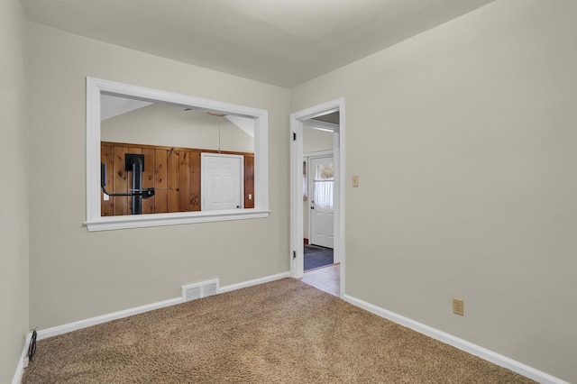 carpeted spare room with vaulted ceiling