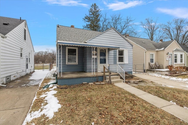 bungalow with a shingled roof, a porch, and fence