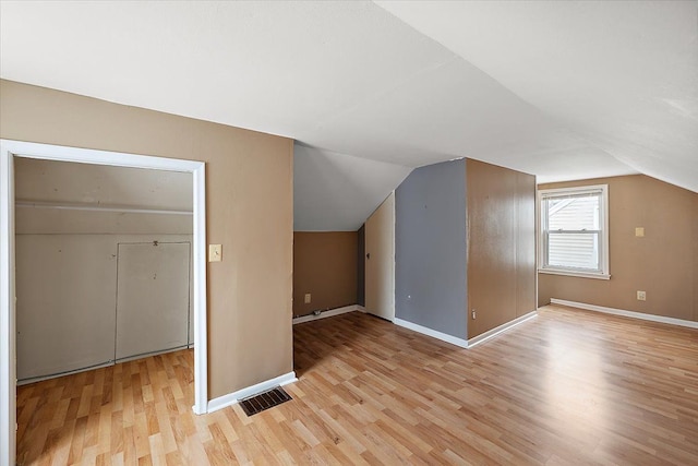 bonus room featuring light wood-style floors, visible vents, vaulted ceiling, and baseboards