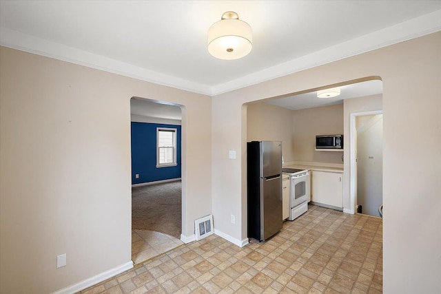 kitchen featuring visible vents, arched walkways, baseboards, appliances with stainless steel finishes, and light countertops