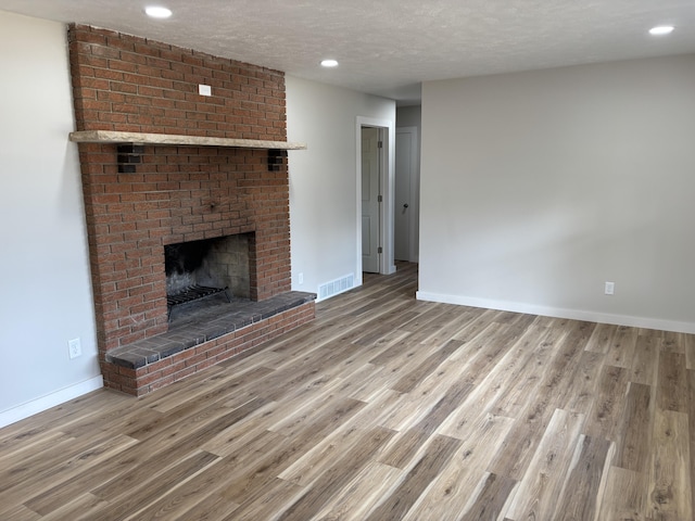 unfurnished living room with hardwood / wood-style floors, a textured ceiling, and a fireplace