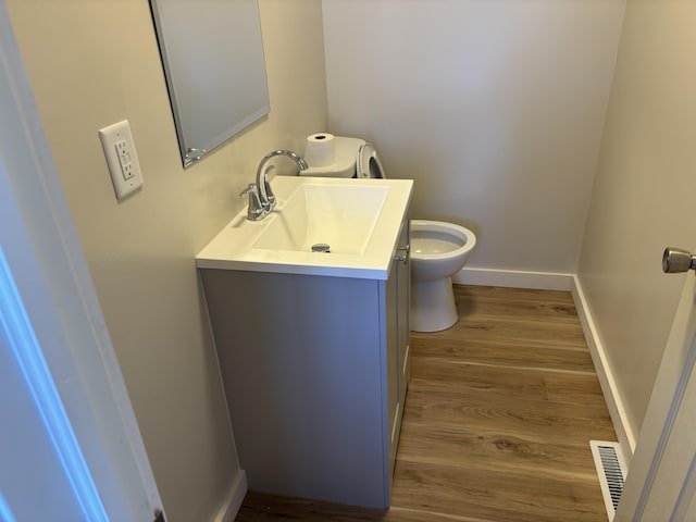 bathroom with vanity, toilet, and hardwood / wood-style floors